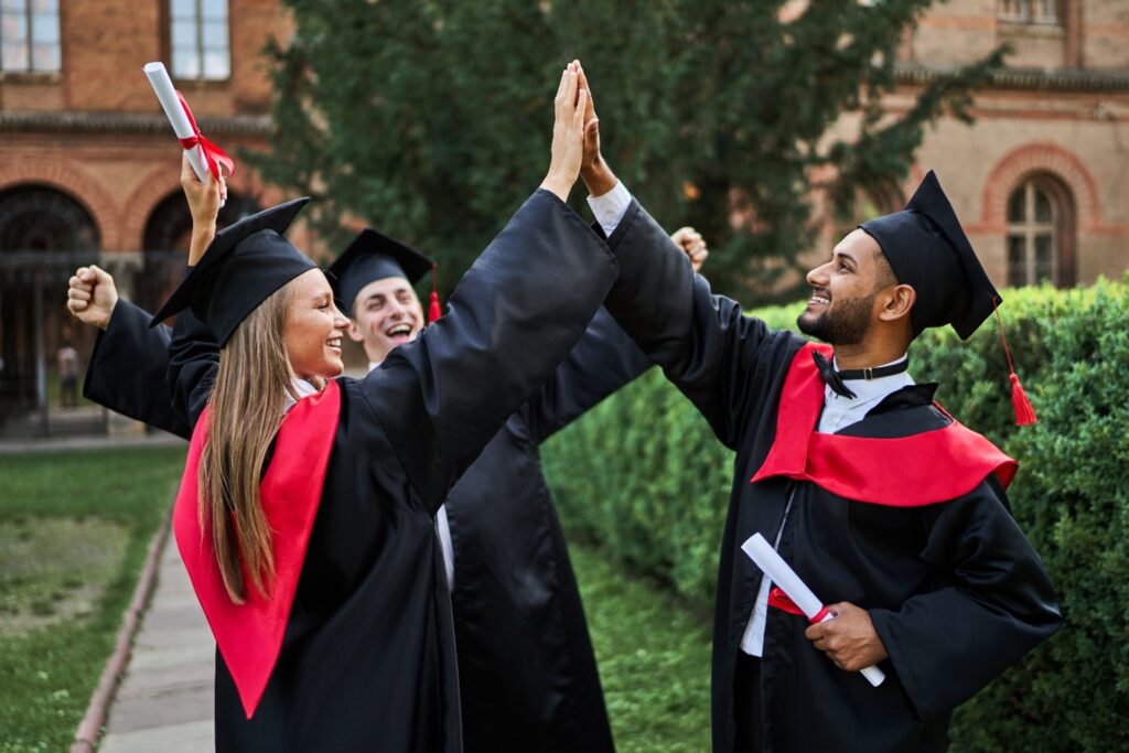 studenti con il tocco che e la toga che festeggiano con il diploma in mano