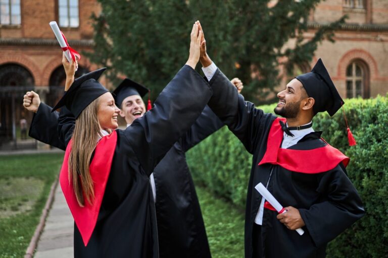 studenti con il tocco che e la toga che festeggiano con il diploma in mano